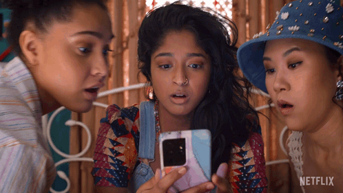 Three Women Are Looking At A Cell Phone With Netflix Written On The Bottom GIF