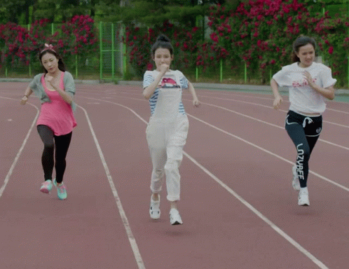 Three Women Are Running On A Track And One Of Them Is Wearing A White Shirt That Says Peace GIF