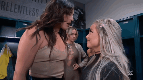 Three Women Are Standing In A Locker Room With A Sign That Says Relentless GIF