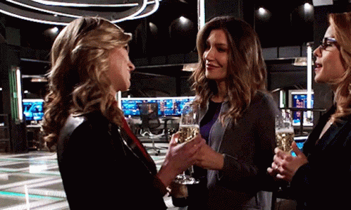 Three Women Are Standing Next To Each Other Holding Champagne Glasses And Talking . GIF