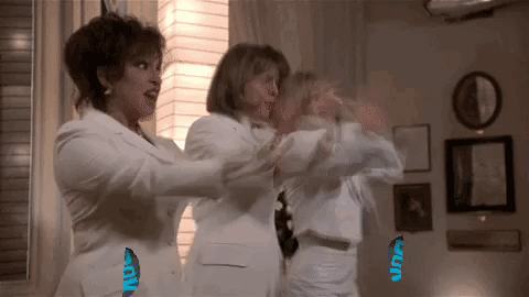 Three Women in White Suits Standing in Living Room