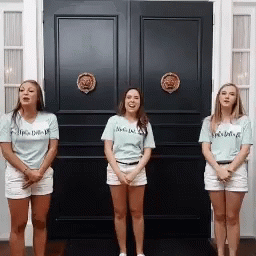 Three Women Standing In Front Of A Black Door With One Wearing A Shirt That Says I 'M A Delta GIF