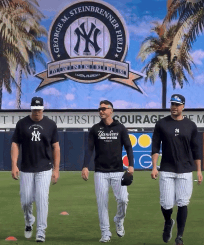three yankees baseball players are walking in front of a george m. steinbrenner field sign