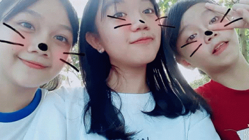 Three Young Girls Are Posing For A Picture Together And One Of Them Has A Cat Face Drawn On Her Face . GIF
