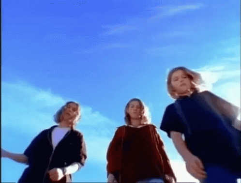 three young people are standing in front of a blue sky .