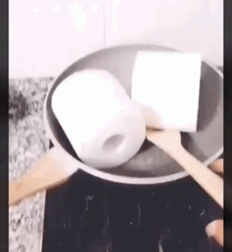 Toilet Paper Being Cooked in Frying Pan With Wooden Spoon