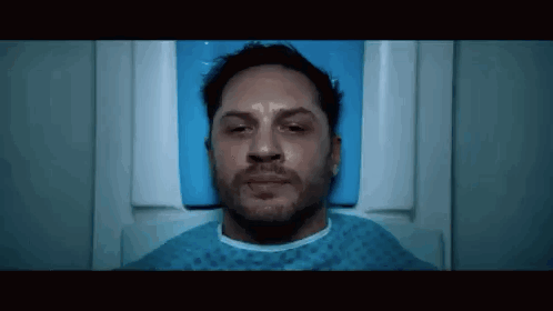 Tom Hardy Is Laying In A Hospital Bed With His Eyes Closed And A Beard . GIF