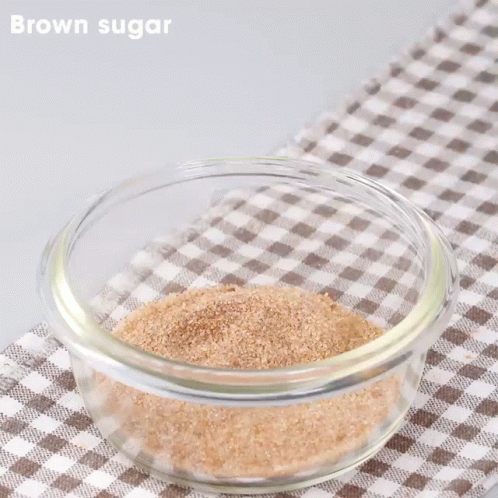 Tongs Stirring Brown Sugar in Glass Bowl