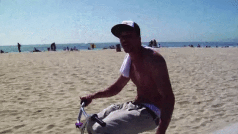 Topless Man Riding Bike By The Beach GIF