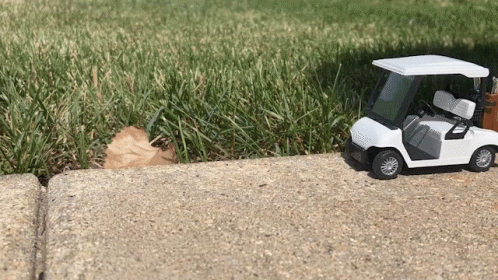 Toy Golf Cart On Sidewalk By Golf Course GIF
