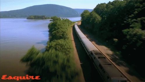 Train Going Down Tracks Next To Water With Esquire GIF