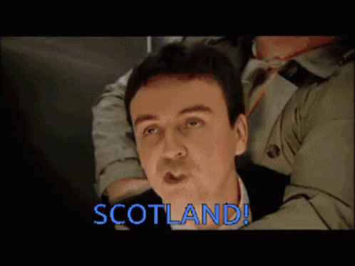 Trench Coat Man Held By Another Saying Scotland GIF