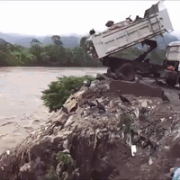 Truck On Pile Of Rocks Near River GIF