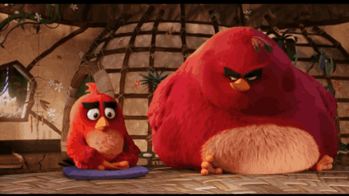 Two Angry Birds Sitting Next To Each Other On A Table GIF