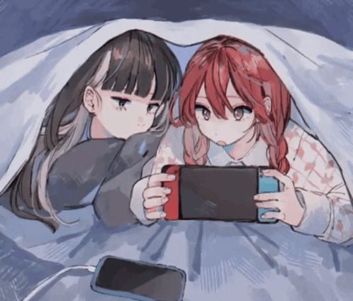 Two Anime Girls Laying Under A Blanket Playing A Game GIF
