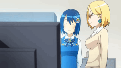 Two Anime Girls Standing Next To Each Other In Front Of A Tv GIF