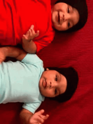 Two Babies Laying on Red Blanket