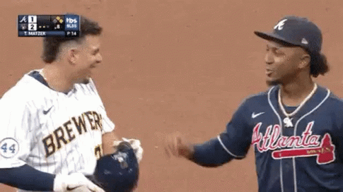 Two Baseball Players Are Hugging Each Other On The Field . GIF