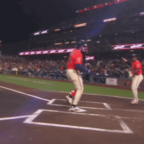 Two Baseball Players Are Jumping In The Air On A Field With A Sign That Says Get Water In The Background GIF