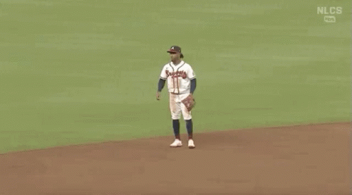 Two Baseball Players Are Shaking Hands On A Field . GIF