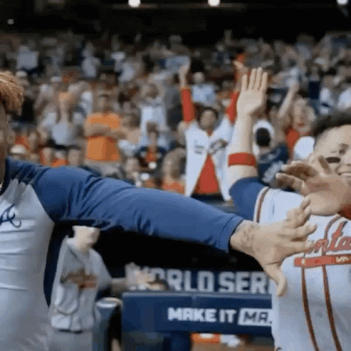 Two Baseball Players Giving Each Other A High Five In Front Of A Sign That Says World Series GIF