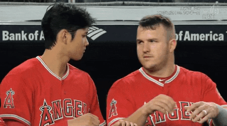 Two Baseball Players Wearing Angels Jerseys Are Talking To Each Other GIF