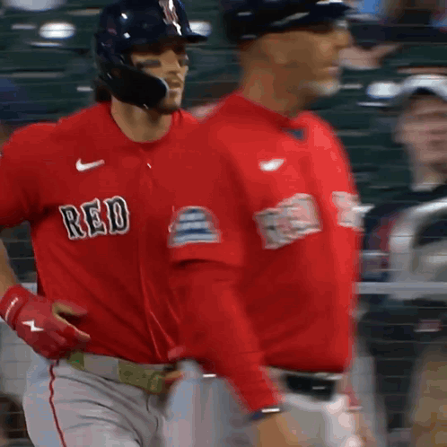 two baseball players wearing red jerseys are walking on a field
