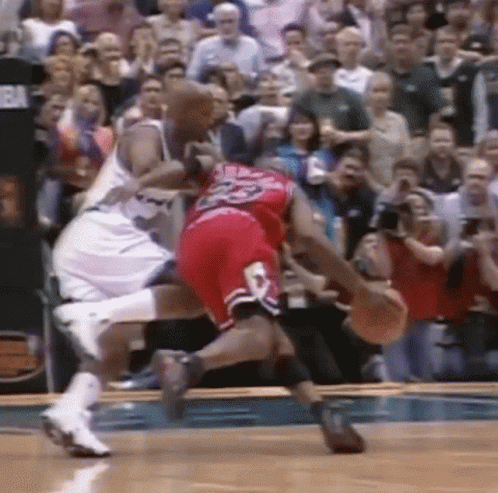 Two Basketball Players Are Fighting For The Ball On A Court . GIF