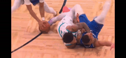 two basketball players are fighting for the ball on a court during a game .
