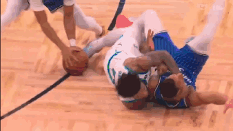 two basketball players are fighting over a basketball on a wooden court .