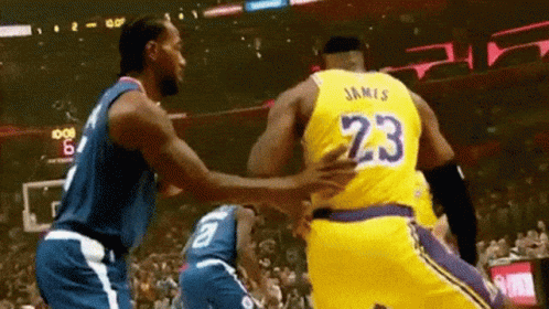 Two Basketball Players Are Hugging Each Other On A Court . GIF