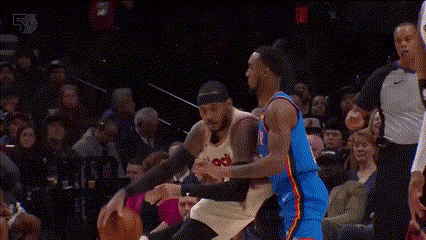 Two Basketball Players Are Playing A Game Of Basketball In Front Of A Crowd . One Player Is Wearing A Number 23 Jersey . GIF