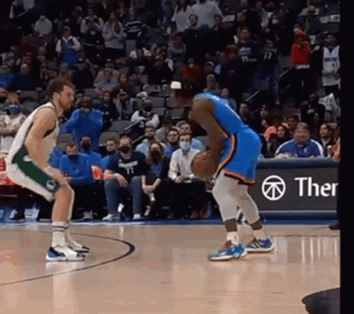 Two Basketball Players Are Playing A Game Of Basketball On A Court With A Crowd Watching . GIF