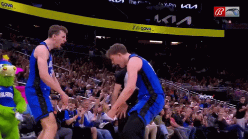 Two Basketball Players Are Standing Next To Each Other In Front Of A Crowd At A Basketball Game Sponsored By Kia GIF
