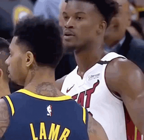 Two Basketball Players Are Talking To Each Other During A Game . One Of The Players Has A Tattoo On His Back . GIF