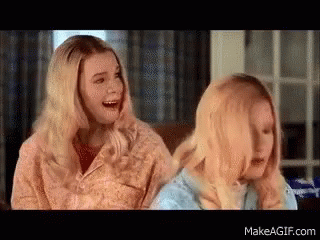 Two Blonde Women Are Sitting Next To Each Other On A Couch Laughing . GIF