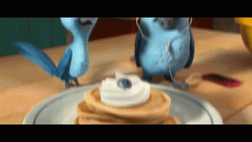 Two Blue Birds Standing Next to Pancakes With Whipped Cream
