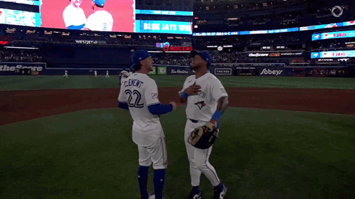 Two Blue Jays Players Talking on Baseball Field