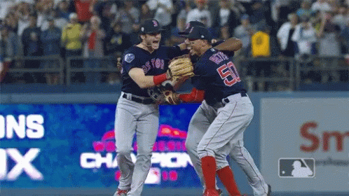 Two Boston Red Sox Players Are Hugging Each Other On The Field GIF