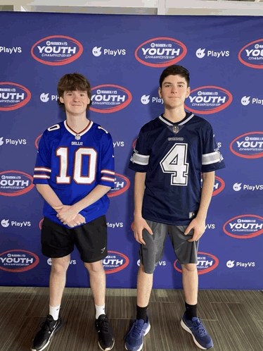 Two Boys Are Standing In Front Of A Wall That Says Playvs Youth GIF