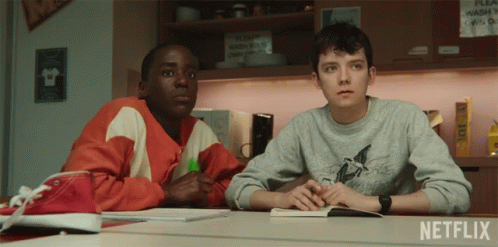 Two Boys Sit At A Table In Front Of A Netflix Sign GIF