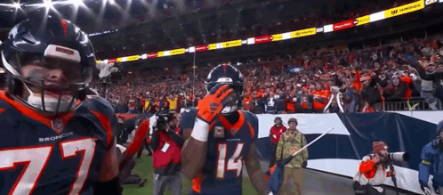 Two Broncos Football Players Standing on Field
