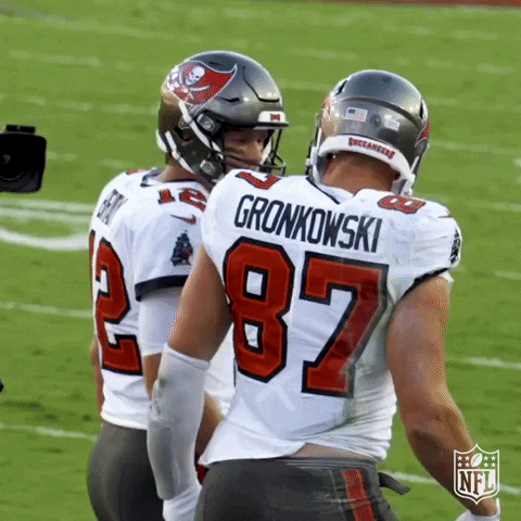 Two Buccaneers Football Players Greet Each Other On The Field During A Game GIF
