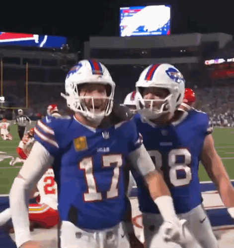 Two Buffalo Bills Players Are Standing On The Field GIF