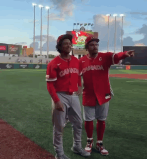 Two Canadian Baseball Players Stand On A Field GIF