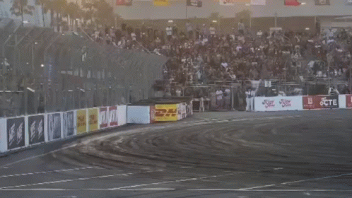 Two Cars Are Drifting On A Track With A Crowd In The Background And A Sign That Says Jcte GIF