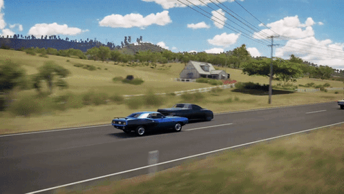 Two Cars Are Driving Down A Road In Front Of A Farm GIF