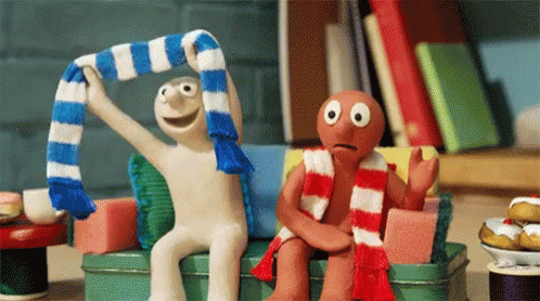 Two Cartoon Characters Sitting On Couch One Wearing Scarf GIF