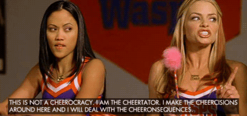 Two Cheerleaders Are Standing In Front Of A Sign That Says Waste GIF