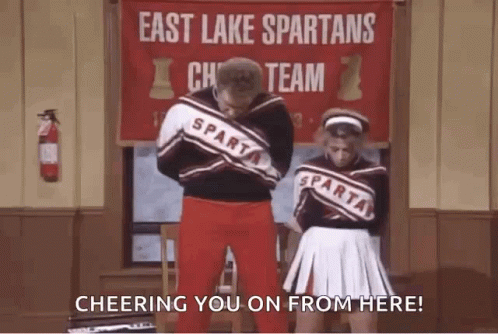 Two Cheerleaders In Front Of East Lake Spartans Cheer Team Banner GIF